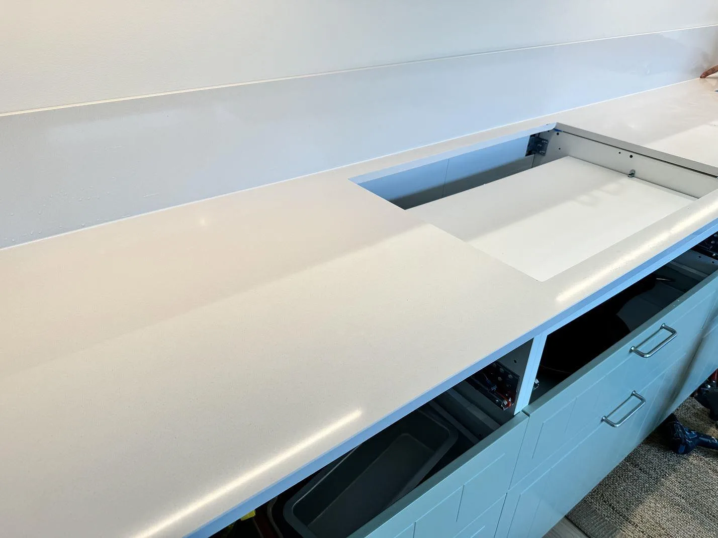 Polerad köksbänkskiva i Silestone Miami White med diskhoöppning och lågt stänkskydd under montering i Bunkeflostrand.