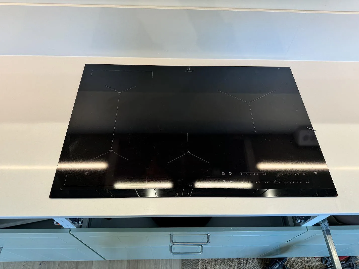 Svart häll monterad i en vit polerad Silestone Miami White köksbänkskiva med stänkskydd i Bunkeflostrand.