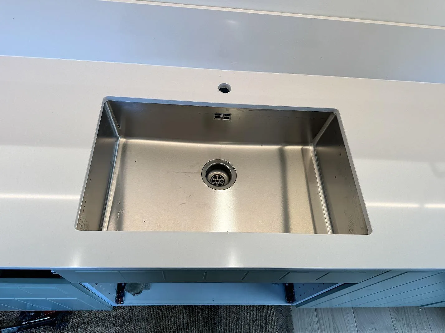 Underlimmad rostfri diskho i en vit polerad Silestone Miami White bänkskiva med blandarhål och stänkskydd i Bunkeflostrand.