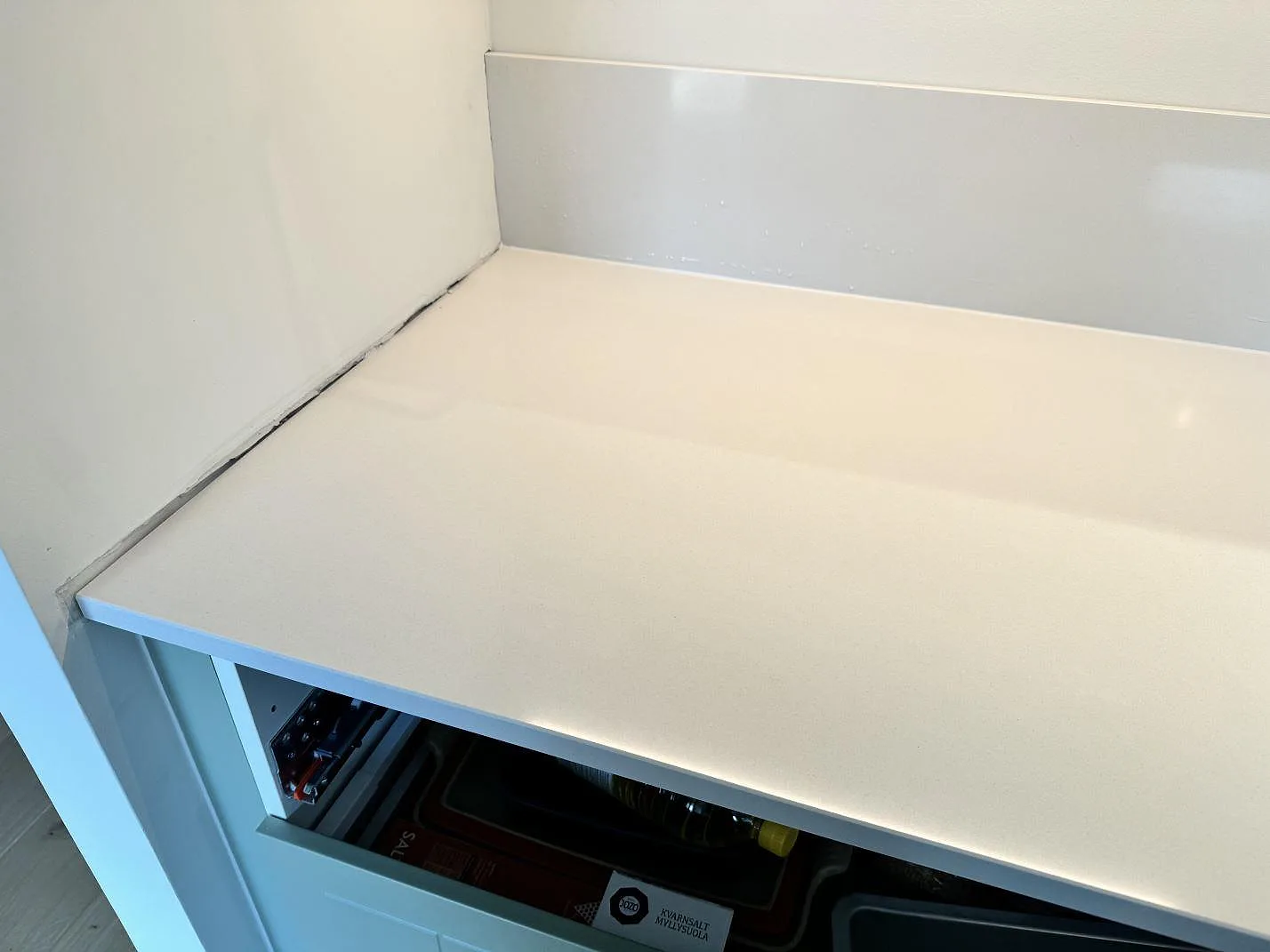 Närbild på vit polerad Silestone Miami White bänkskiva med uppvikt stänkskydd och ljus ådring i Bunkeflostrand.