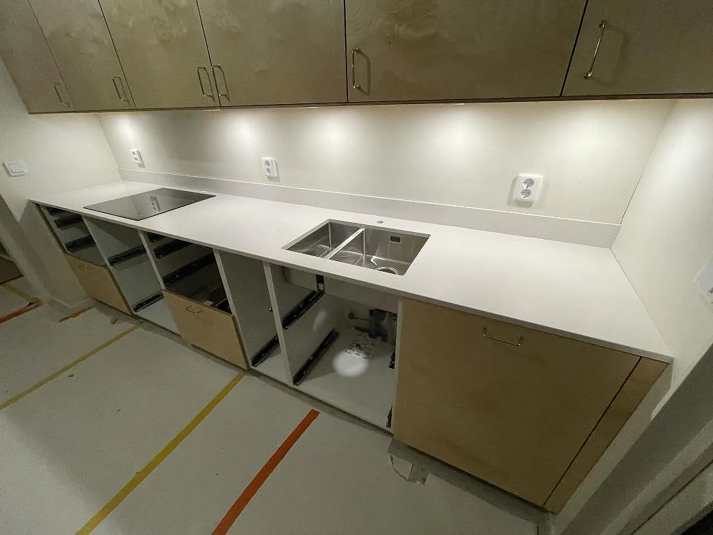 L-format kök med polerad köksbänkskiva i vit Silestone Miami White komposit, underlimmad dubbel rostfri diskho och svart induktionshäll i Göteborg.