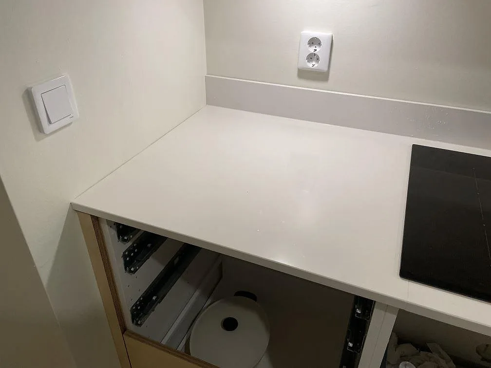 Hörndel av polerad Silestone Miami White köksbänkskiva i komposit bredvid svart häll och trästommar i Göteborg.