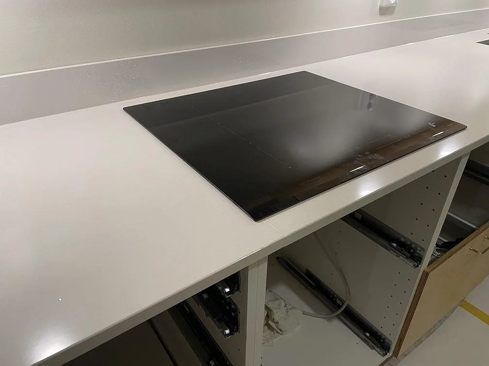 Svart induktionshäll infälld i polerad vit Silestone Miami White kompositbänkskiva med låg stänkkant i Göteborg.