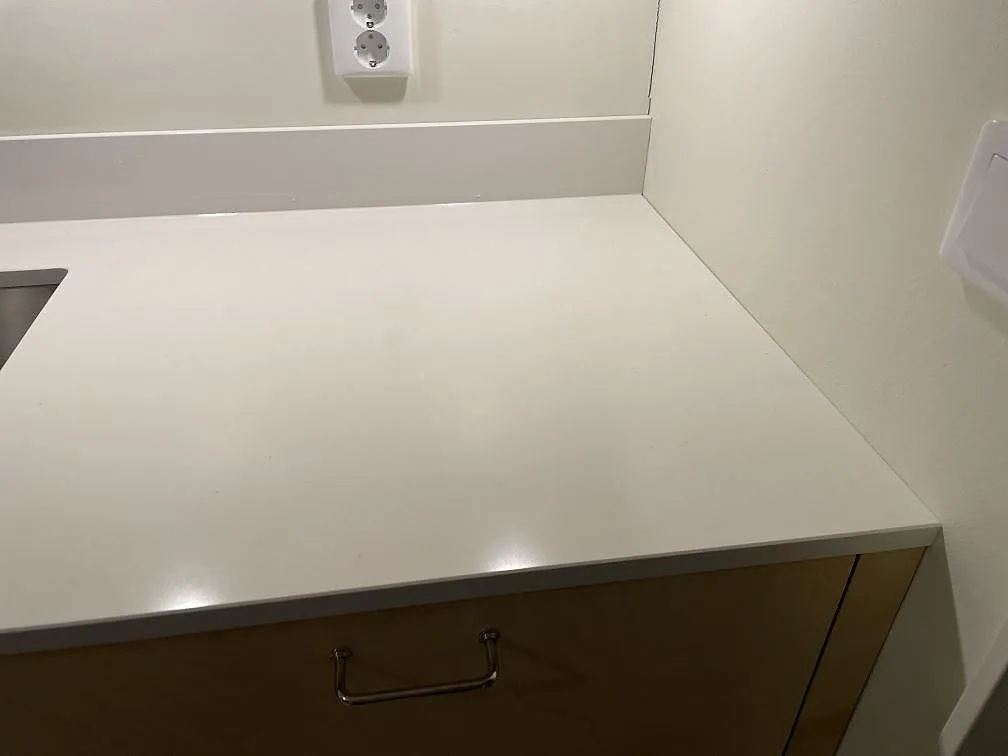 Vit polerad Silestone Miami White kompositbänkskiva med låg stänkkant och synlig rostfri diskho i ett kök i Göteborg.