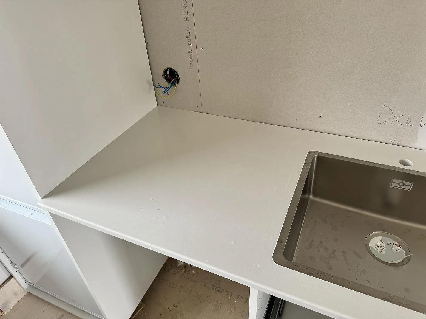 Diskbänk i polerad Silestone Miami White med rostfri diskho och blank vit yta i ett kök under montering i Jönköping.