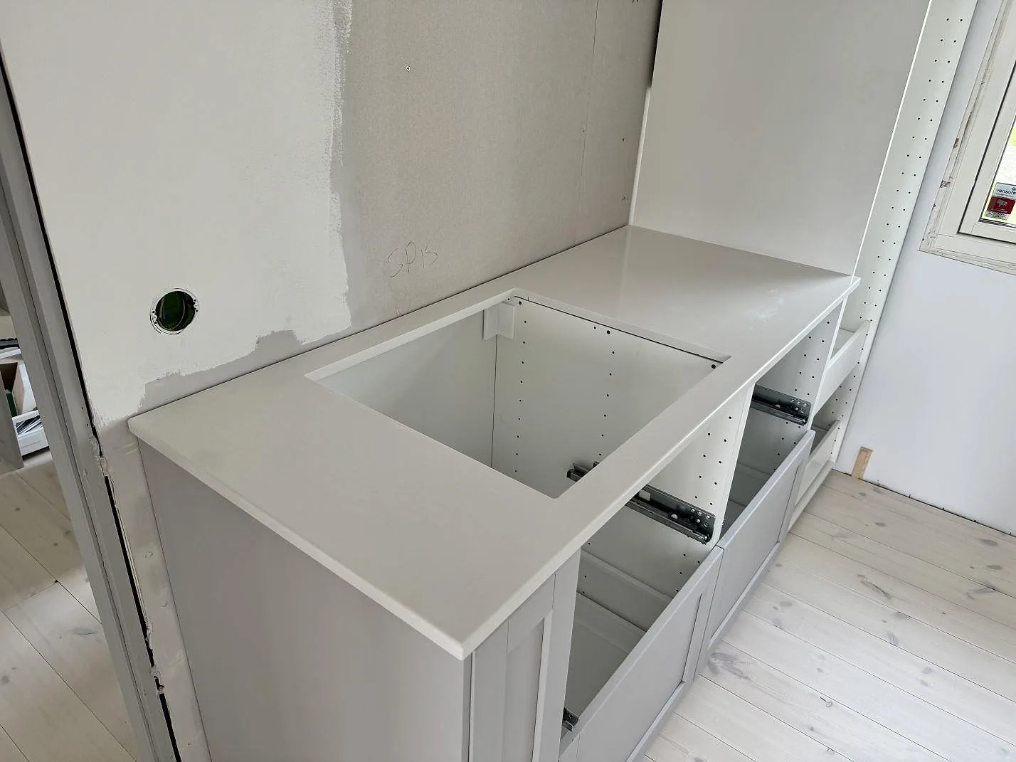 Vit köksbänkskiva i polerad Silestone Miami White med öppning för spisområdet på vita köksstommar i Jönköping.