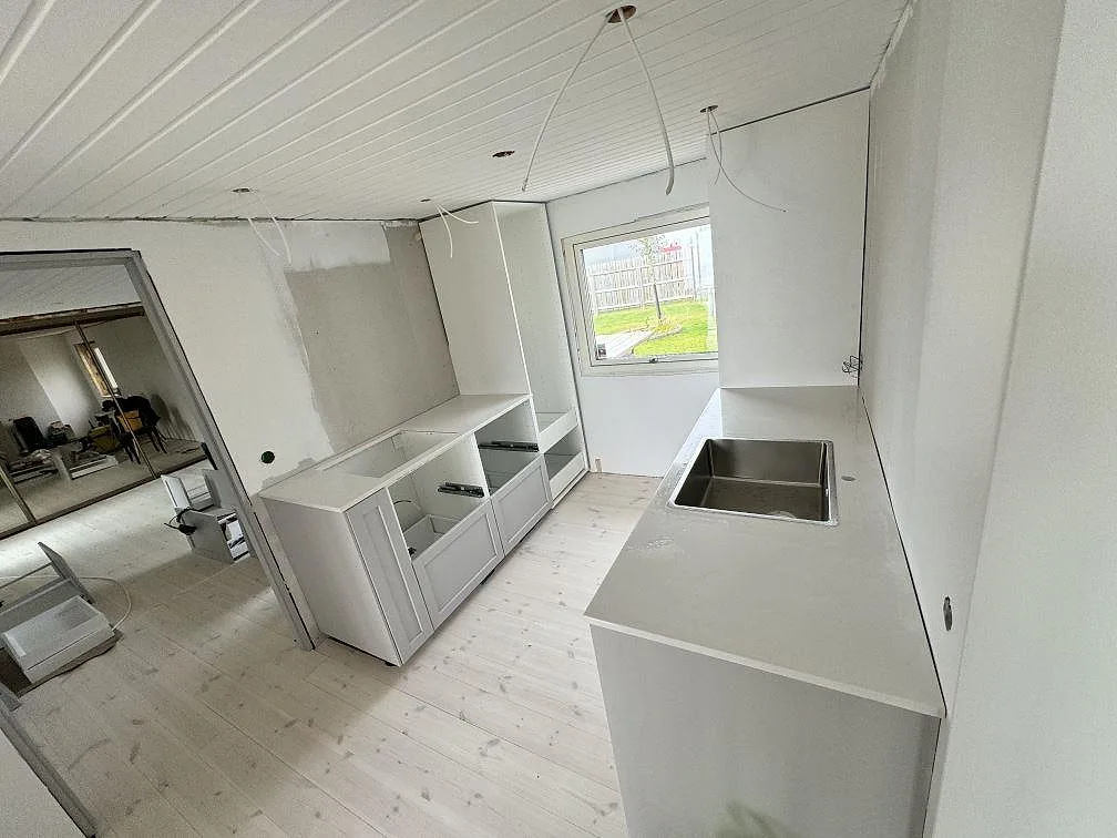 Översiktsbild av kök under montering i Jönköping med polerad Silestone Miami White på två bänkrader och rostfri diskho.