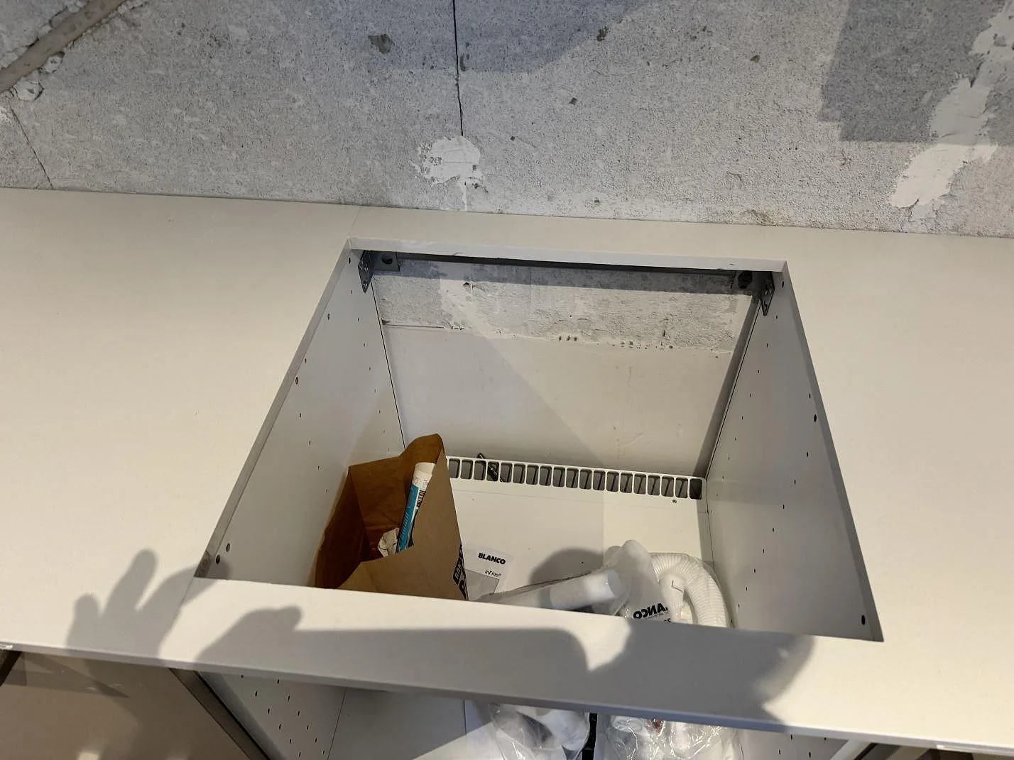 Detalj av rektangulärt hällurtag i vit polerad Silestone Miami White bänkskiva under montering i Kävlinge.