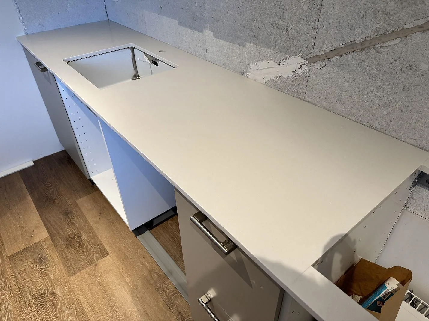L-formad köksbänkskiva i vit polerad Silestone Miami White komposit med underlimmad rostfri diskho i ett kök i Kävlinge.