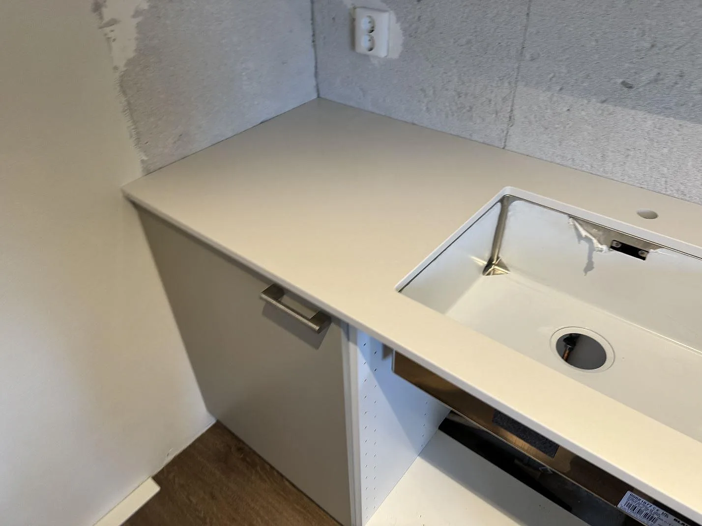Vit Silestone Miami White kompositbänkskiva med underlimmad rostfri diskho, blandarhål och öppen skåpstomme i Kävlinge.