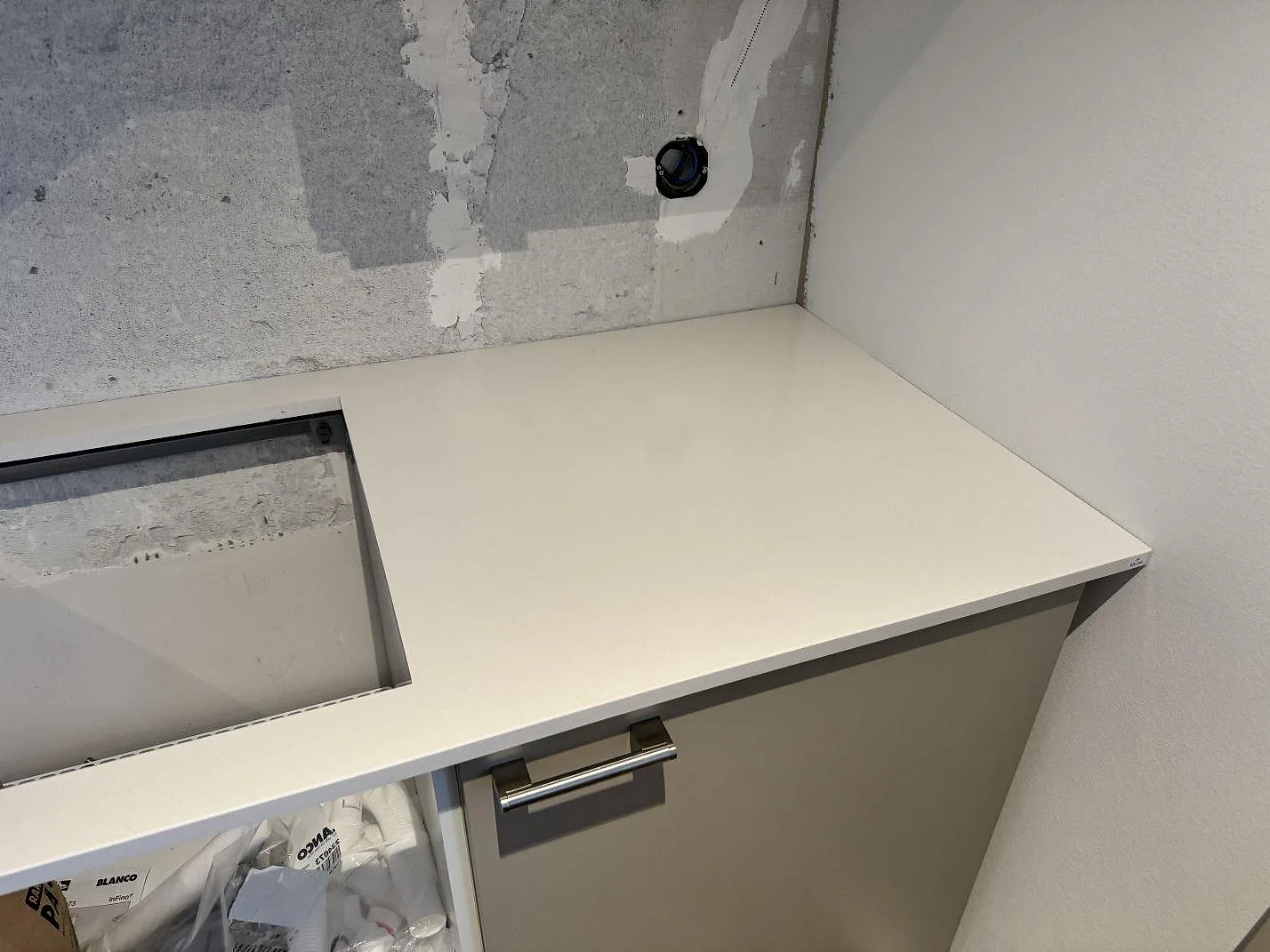 Polerad Silestone Miami White kompositbänkskiva med rektangulärt hällurtag och ljusa skåpstommar i ett kök i Kävlinge.