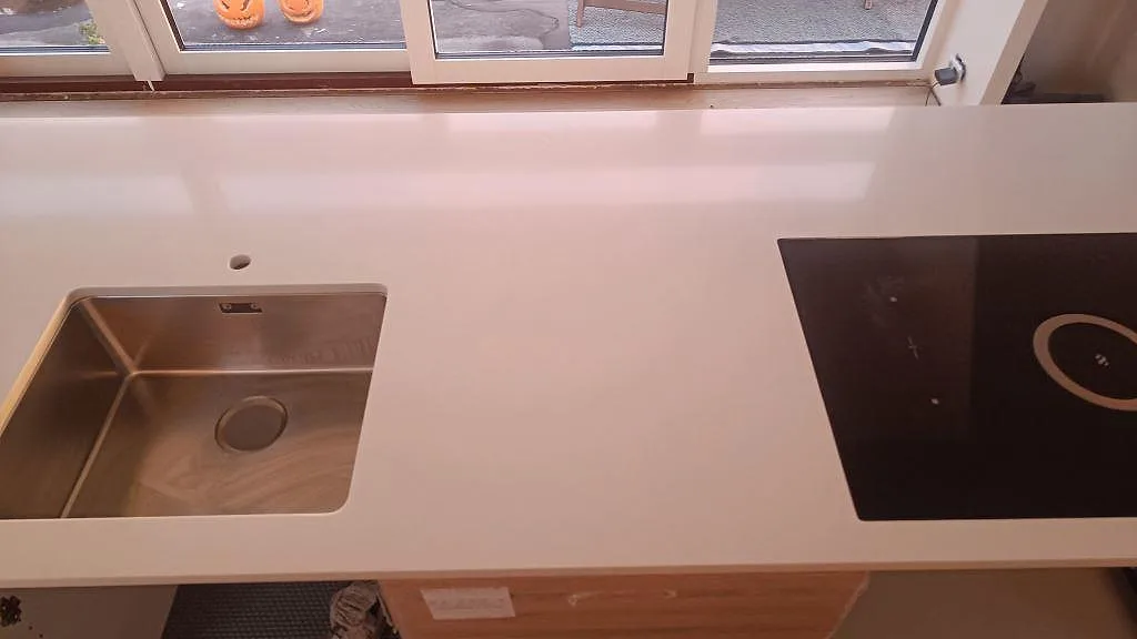 Närbild ovanifrån på induktionshäll i vit Silestone Miami White bänkskiva i ett kök i Karlslunde.