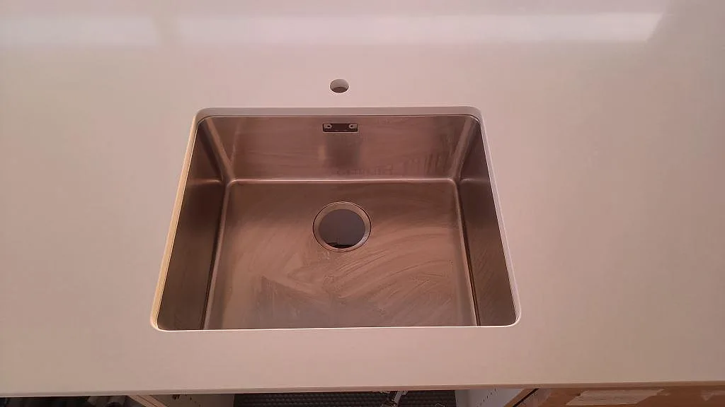 Vit Silestone Miami White köksbänkskiva sedd ovanifrån med stor underlimmad rostfri diskho i ett kök i Karlslunde.