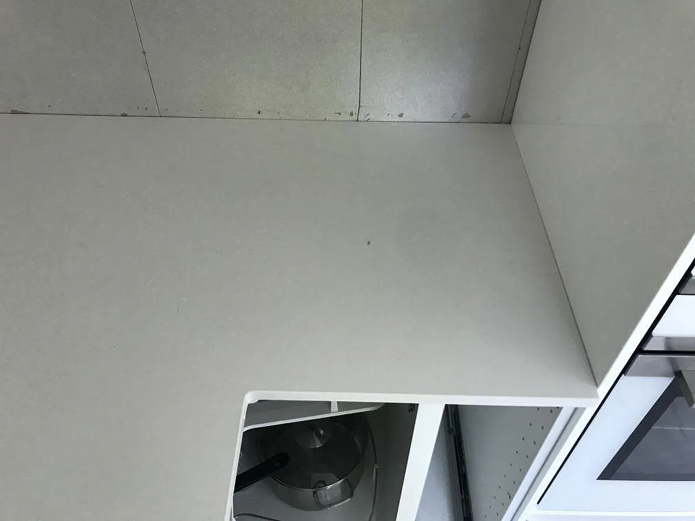 Vit Silestone Miami White köksbänkskiva i kvartskomposit monterad i en hörnlösning mot omålad vägg i ett kök i Kungälv.