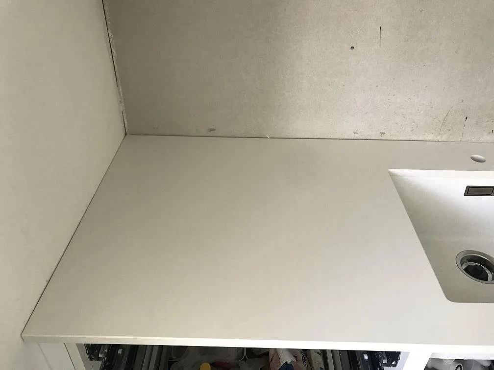 Vit Silestone Miami White köksbänkskiva mot väggen med underlimmad diskho och separat borrat blandarhål i stenen i ett kök i Kungälv.