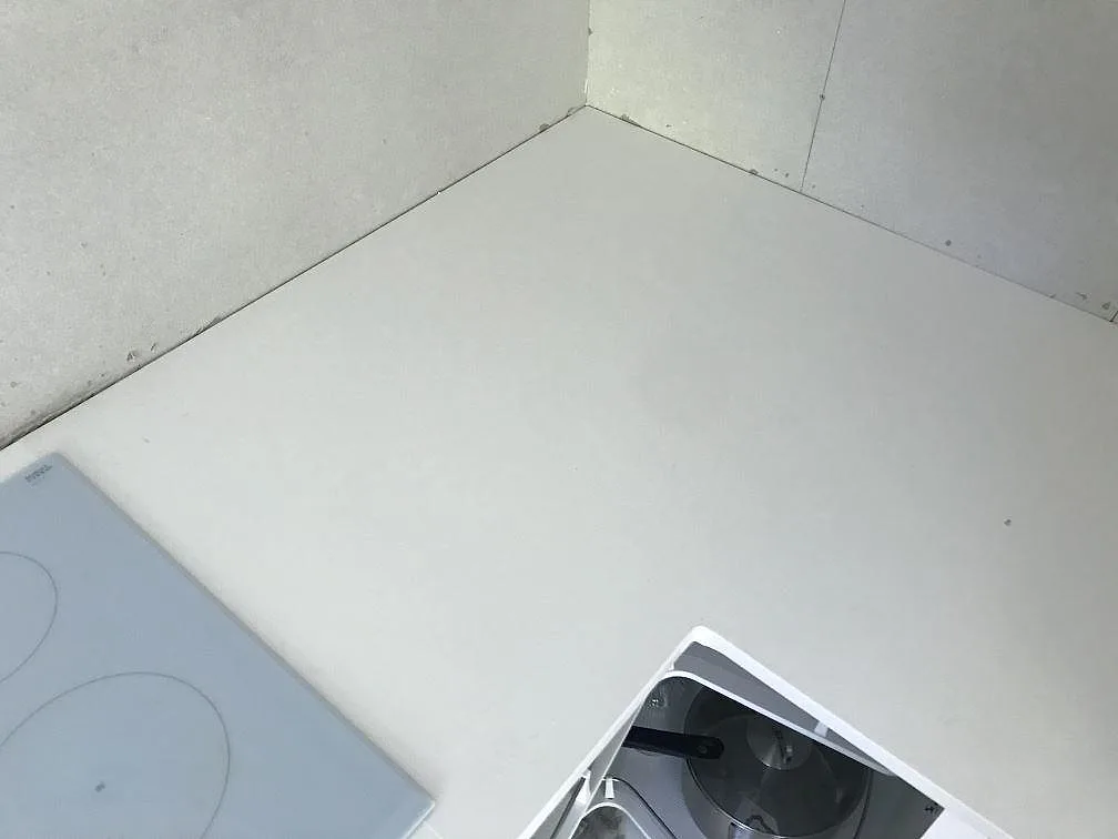 Polerad Silestone Miami White bänkskiva i hörnet av ett kök med induktionshäll under montering i Kungälv.