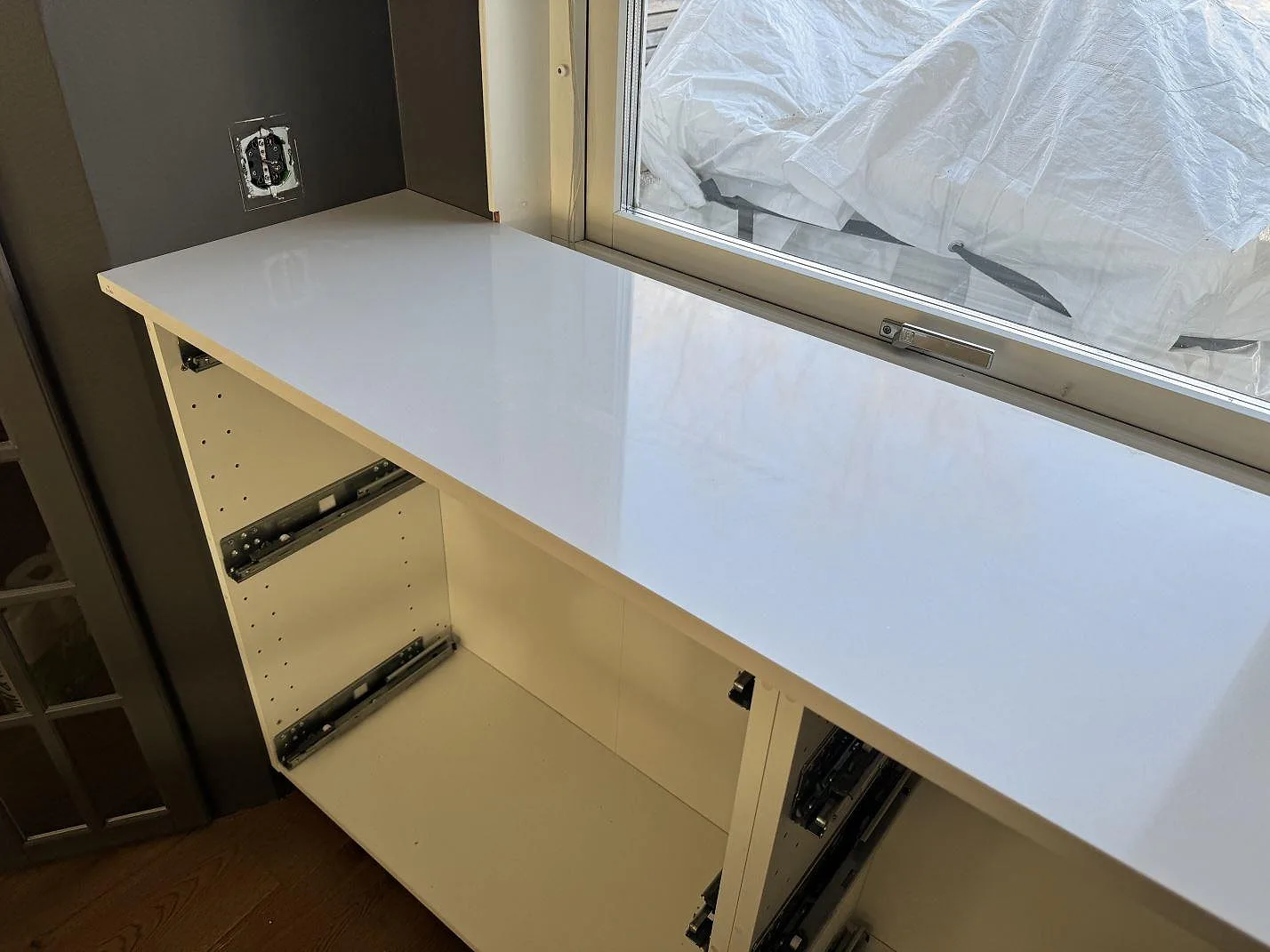Lång bänkrad i polerad Silestone Miami White komposit monterad vid fönster på öppna köksstommar i Kungälv.