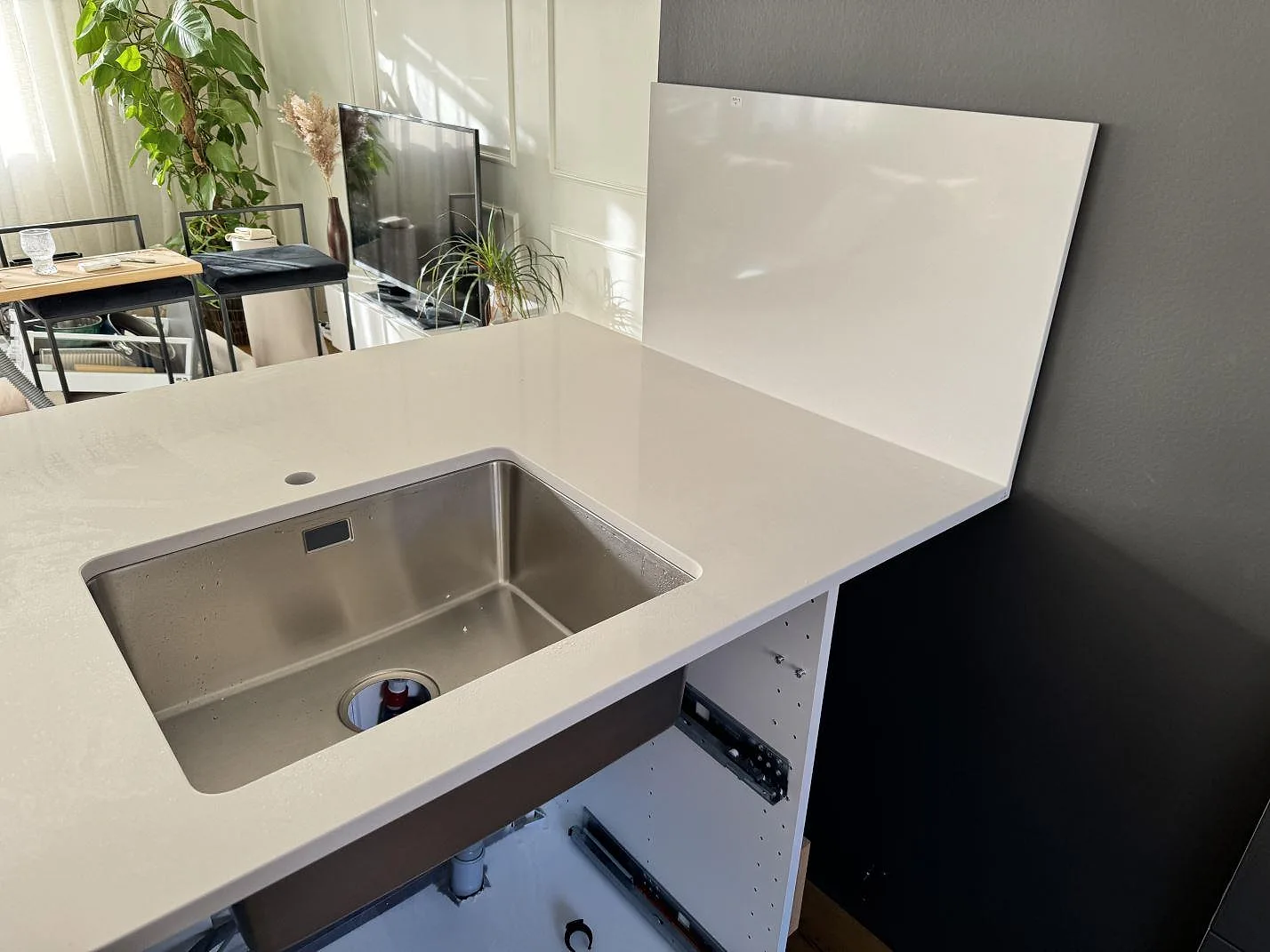 Köksbänkskiva i vit polerad Silestone Miami White komposit med underlimmad rostfri diskho och stänkskydd i ett kök i Kungälv.