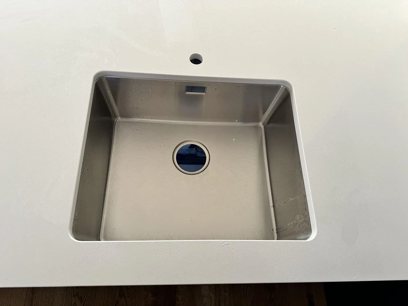 Närbild av underlimmad rostfri diskho i vit polerad Silestone Miami White kompositbänkskiva i Kungälv.