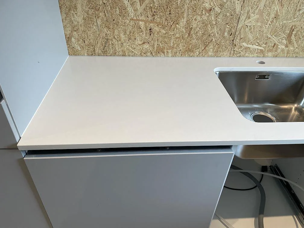 Vit köksbänkskiva i polerad Silestone Miami White med rostfri diskho monterad under stenen i ett kök under montering i Lyckeby.