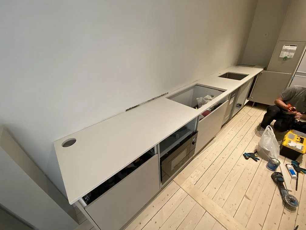 Köksbänkskiva i vit Silestone Miami White, polerad, längs en lång vägg med underlimmad rostfri diskho i ett kök under montering i Malmö.