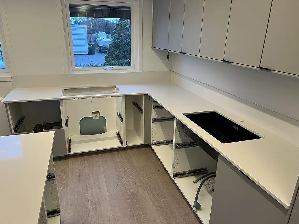 Polerad köksbänkskiva i Silestone Miami White komposit med öppning för diskho, häll och låg stänkkant i Örebro.
