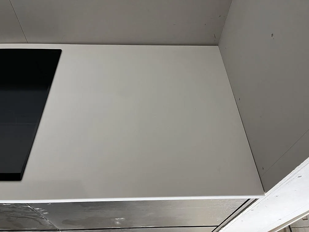Hörnsektion av vit köksbänkskiva i Silestone Miami White med urtag för induktionshäll i ett kök i Rockneby.