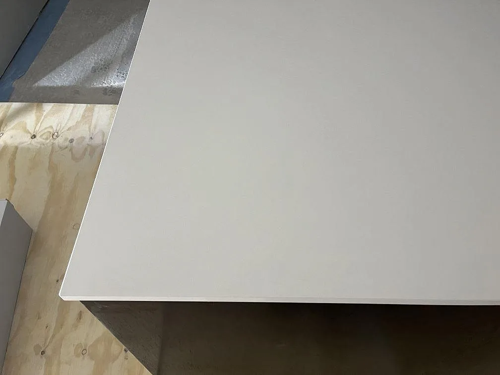 Kant och hörn på en vit köksbänkskiva i Silestone Miami White ovanpå öppna köksstommar i Rockneby.
