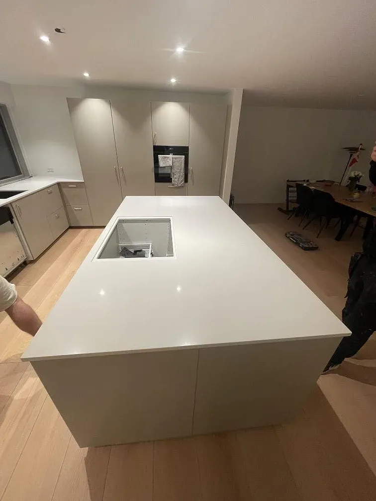 Frilagd köksö i vit Silestone Miami White med urtag för häll, öppen planlösning mot matplats, under montering i Smørum.
