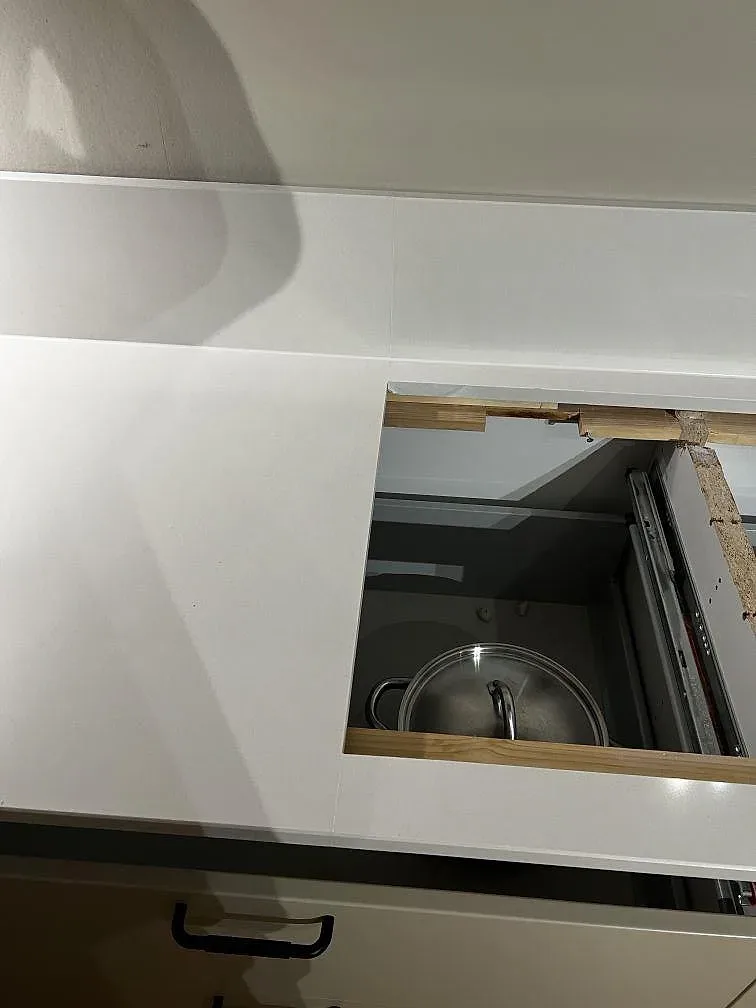 Närbild på vit Silestone Miami White runt en öppnad köksfront, med polerad yta och låg stänkkant under montering i Trelleborg.
