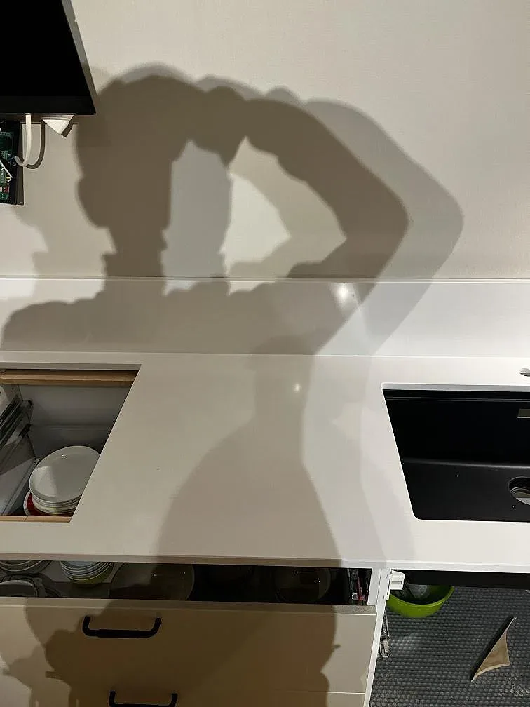 Vit Silestone Miami White runt diskho och öppna stommar, polerad komposit med låg stänkkant i ett kök i Trelleborg.