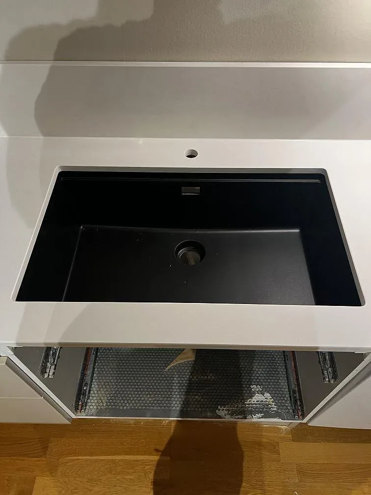 Närbild på underlimmad svart diskho i polerad Silestone Miami White med vit komposityta och låg stänkkant i Trelleborg.