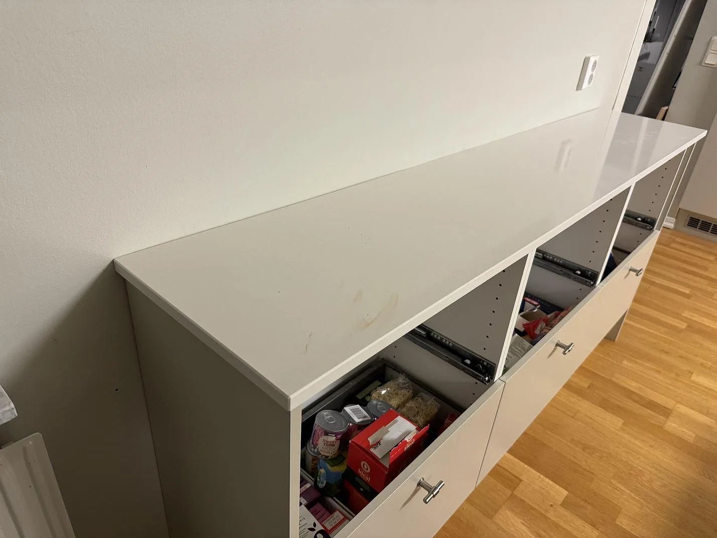 Lång polerad Silestone Miami White bänkskiva med diskret ådring på vit stomme och parkettgolv i Växjö.