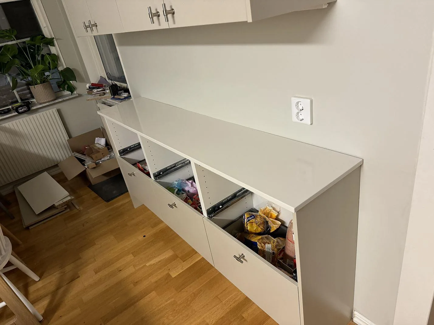 Köksbänkskiva i vit Silestone Miami White, polerad komposit, på låg vit förvaring med öppna fack i Växjö.