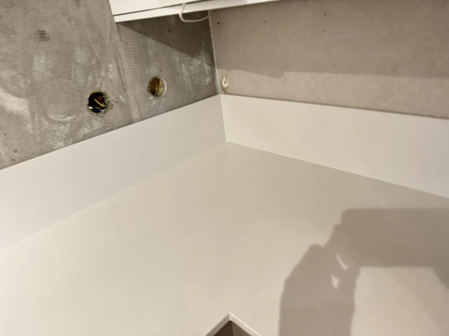 Hörnvy av polerad Silestone Miami White med vit stänkkant och vägguttag under montering i ett kök i Växjö.