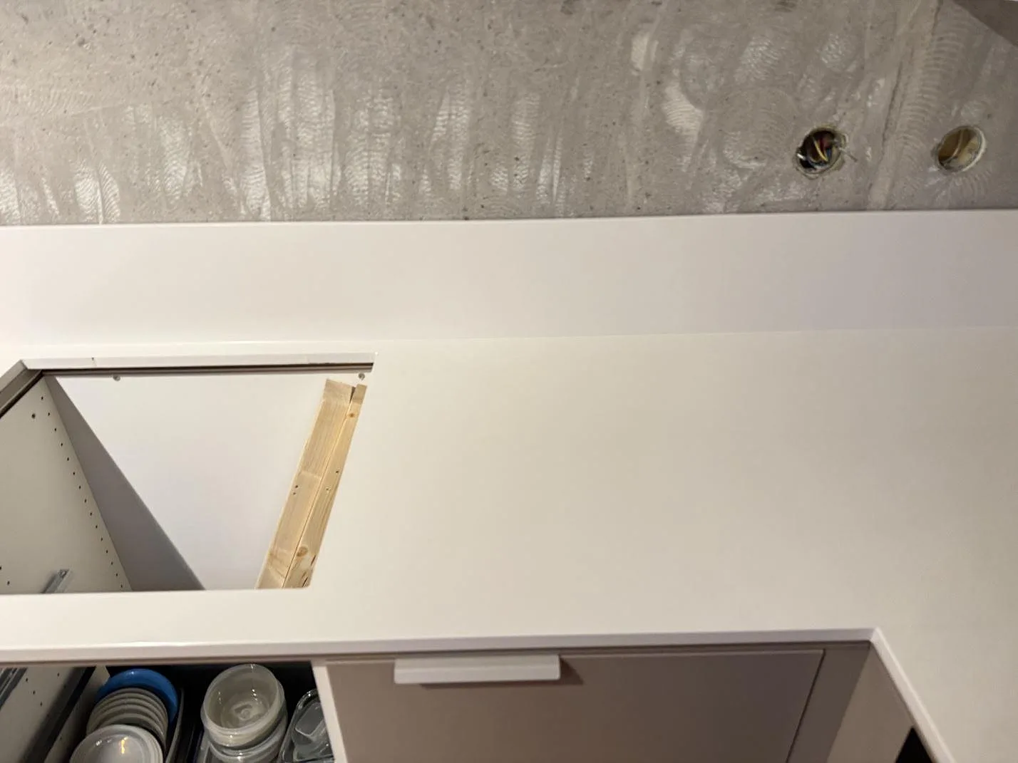 Polerad Silestone Miami White som köksbänkskiva med rektangulärt urtag och låg stänkkant under montering i Växjö.