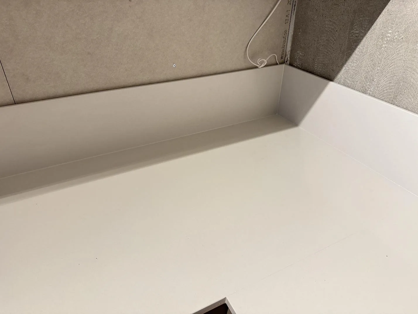 Detalj av vit Silestone Miami White i polerad finish med uppvikt stänkkant i kökshörn i Växjö.