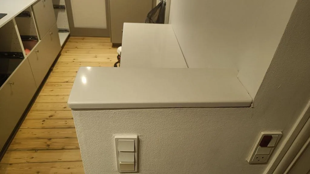 Polerad Silestone Miami White på en kort peninsula och sidobänk i ett kök under montering i Valby.