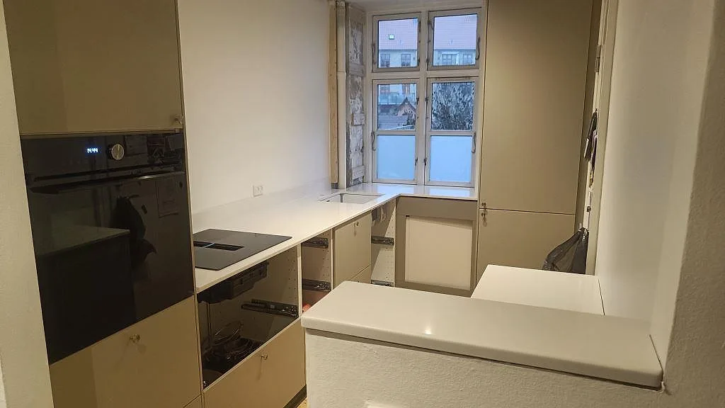 Köksbänkskiva i vit Silestone Miami White, polerad komposit, monterad i ett kompakt kök i Valby.