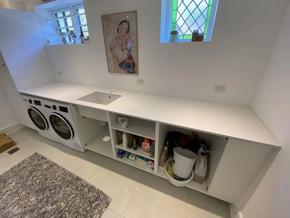 Polerad bänkskiva i vit Silestone Miami White komposit med tvättställ i ett kombinerat badrum och tvättutrymme i Vanløse.
