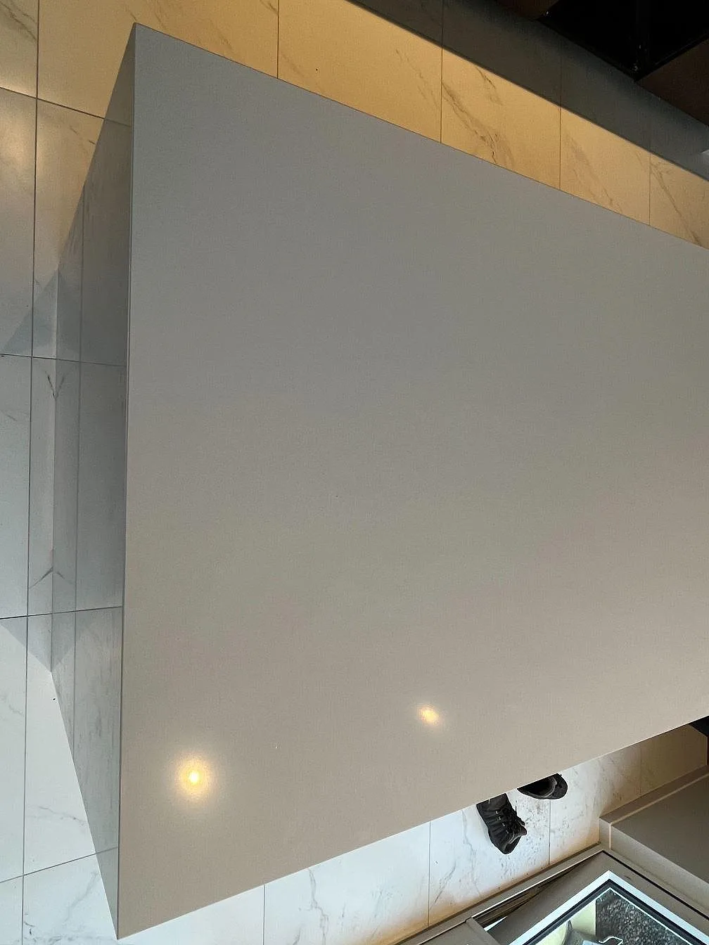 Vit Silestone Miami White köksbänk och bardel mot öppna skåpstommar i ett kök i Varberg.
