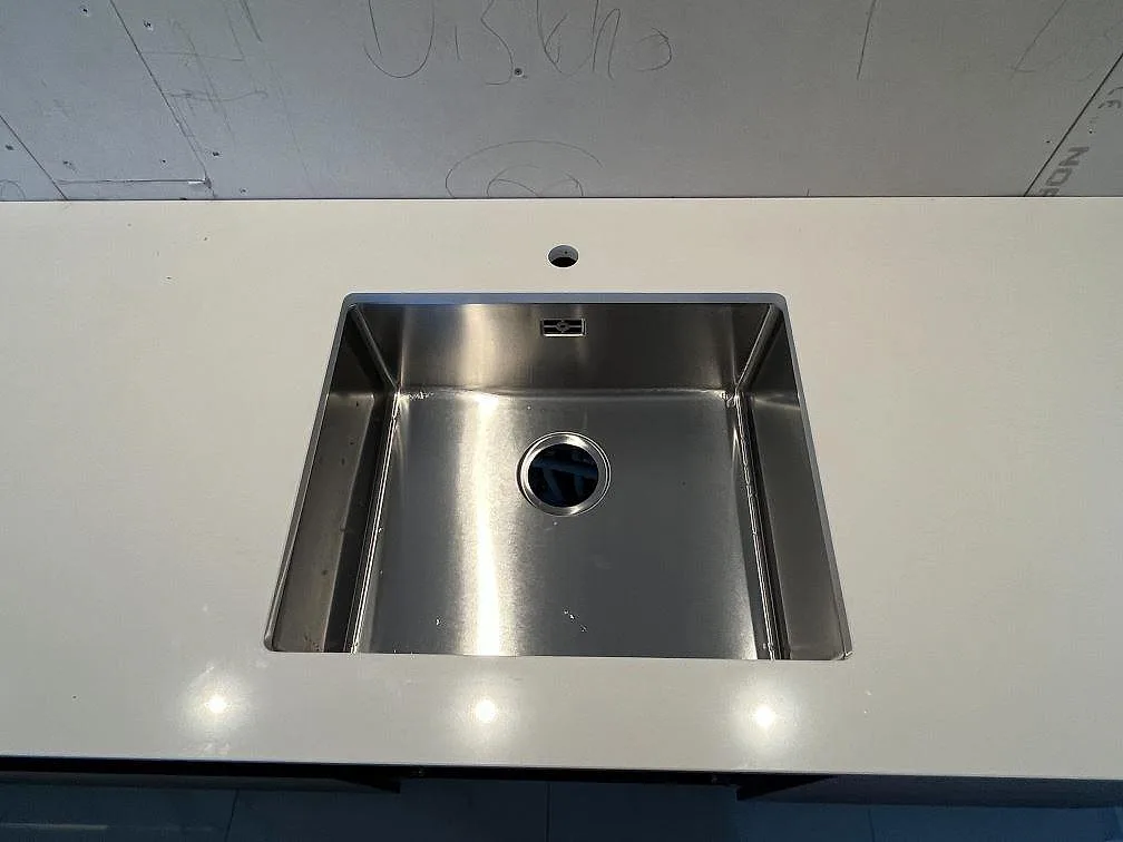Lång köksbänk i polerad vit Silestone Miami White sedd uppifrån i ett kök under montering i Varberg.
