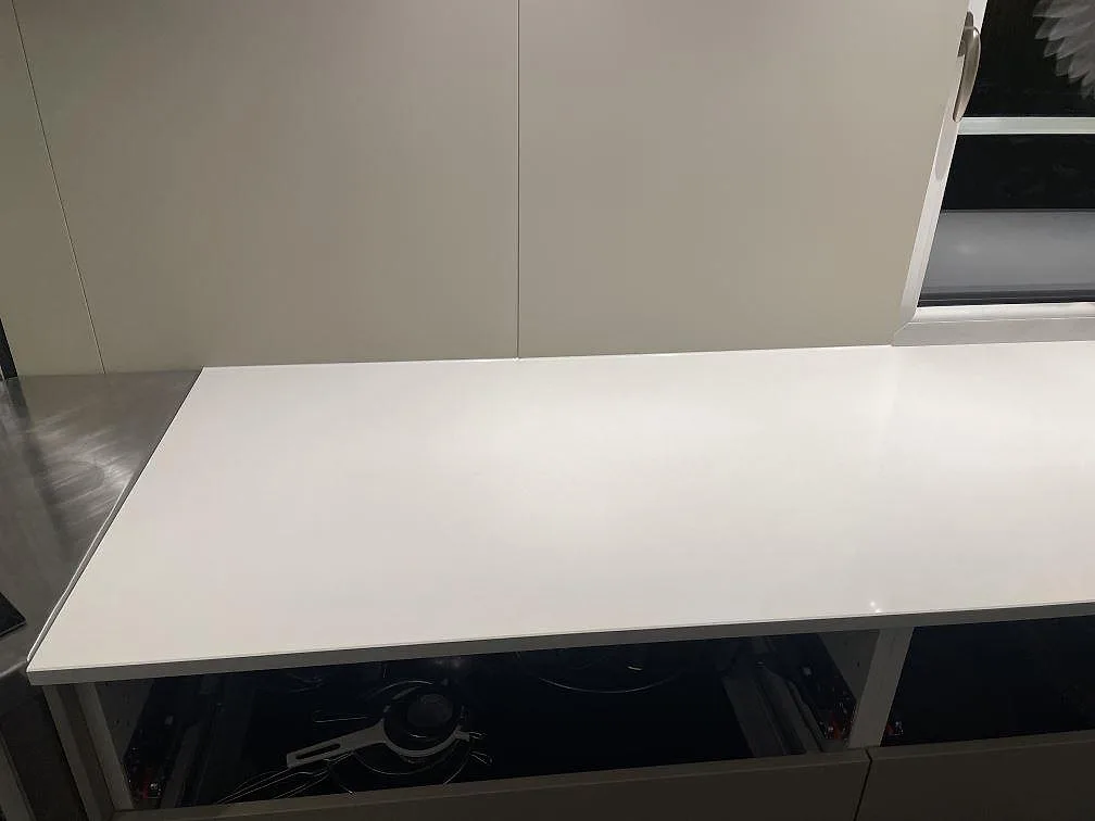 Polerad köksbänkskiva i vit Silestone Miami White mot beige köksluckor i ett kök i Vejbystrand.