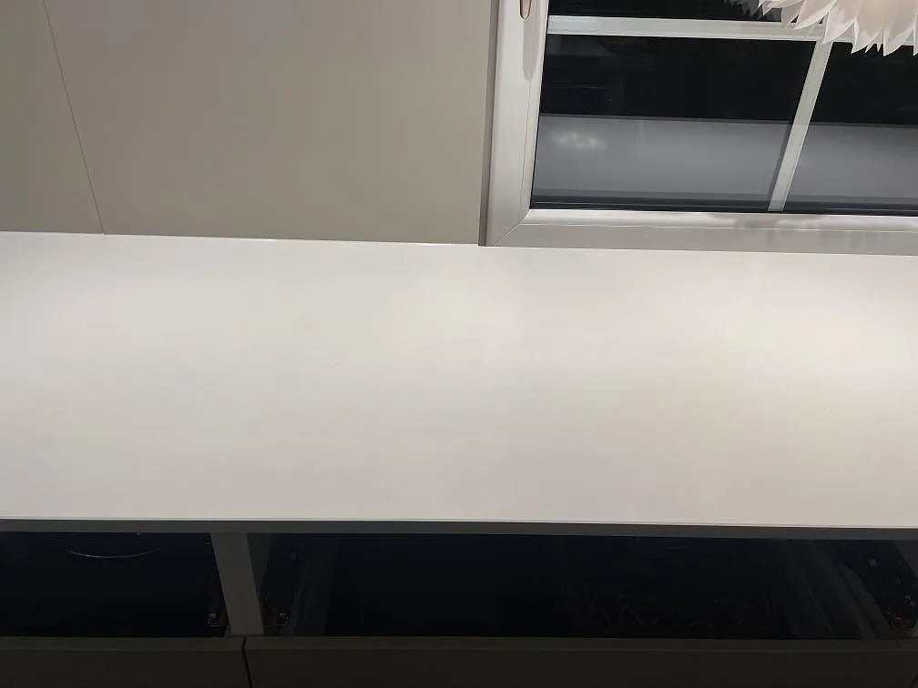 Lång köksbänkskiva i vit Silestone Miami White, polerad yta, under fönster i ett kök i Vejbystrand.