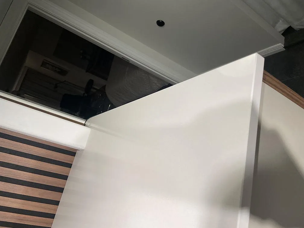 Bänkskiva i vit Silestone Miami White, polerad yta, mot panelvägg och fönster i ett kök i Vejbystrand.