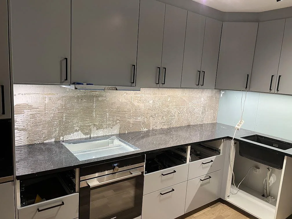 Köksvy med polerad bänkskiva i Silestone Negro Stellar, svart kvartskomposit med ljusa spegelkorn, under montering i Norrtälje.