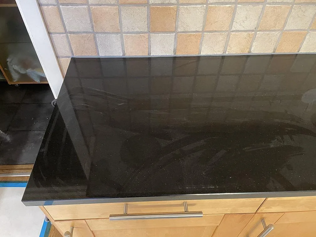 Köksbänkskiva i svart Silestone Negro Tebas, polerad, monterad mot ljusa träluckor i ett kök i Åkarp.