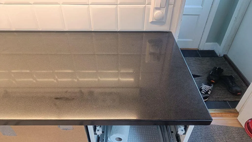 Detalj av den polerade Silestone Negro Tebas ytan och den raka framkanten på köksbänken i Åmål.