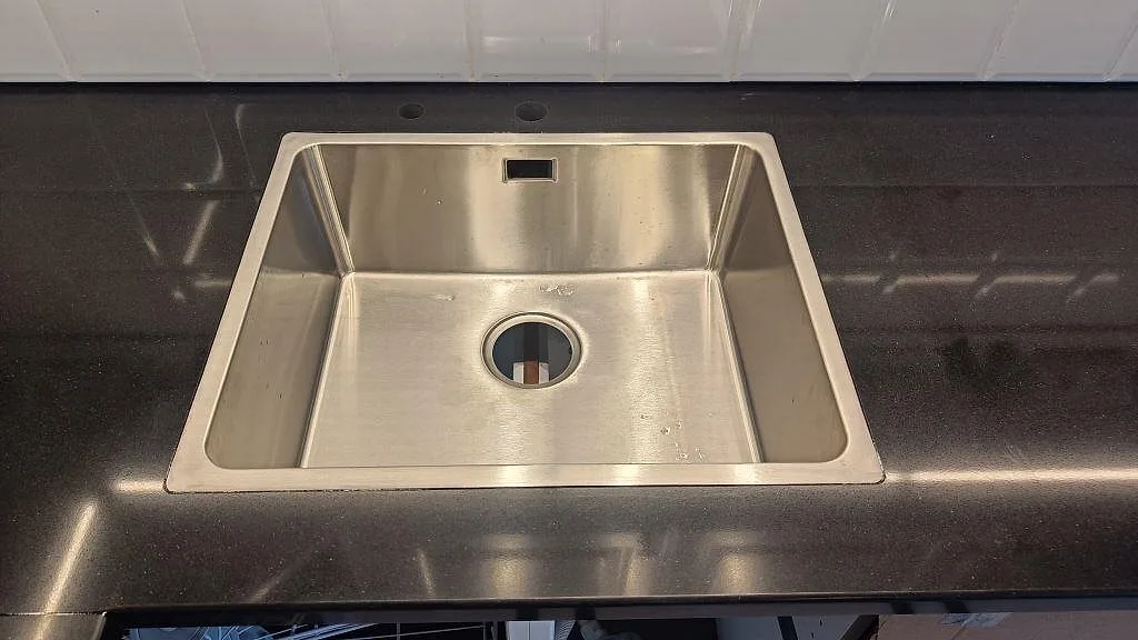 Rostfri diskho med synlig kant i en mörk polerad Silestone Negro Tebas bänkskiva i Åmål.