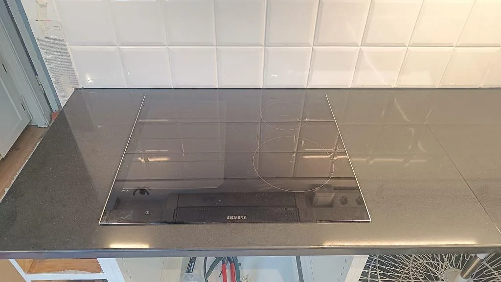 Polerad kompositbänkskiva i Silestone Negro Tebas med svart induktionshäll infälld i köket i Åmål.